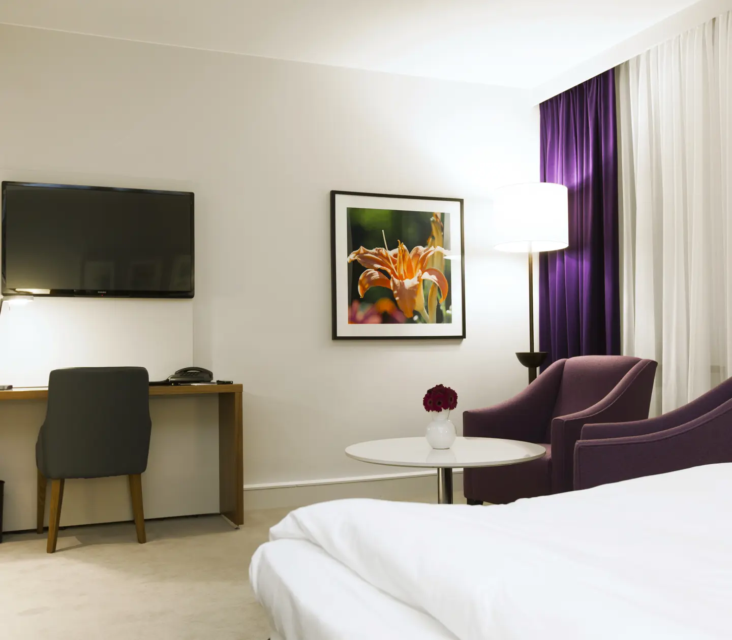 Hotellrum med skrivbord, fåtöljer och tv