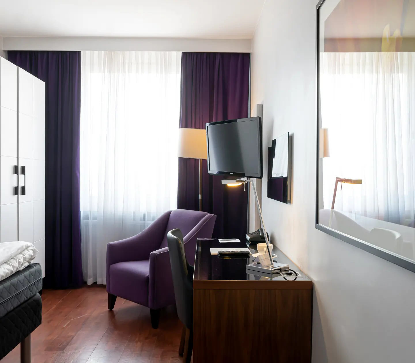 Hotellrum med skrivbord, fåtölj och garderob