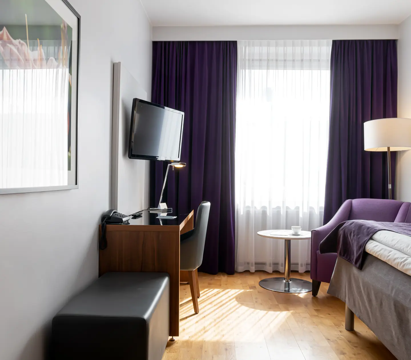 Hotellrum med säng, fåtölj och skrivbord