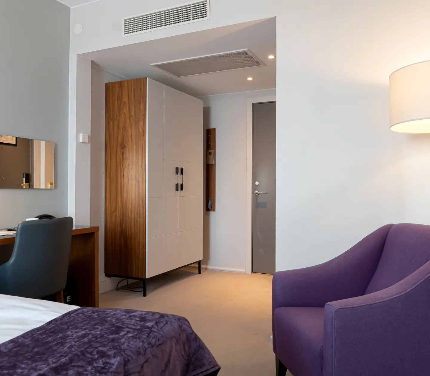 Hotellrum med fåtölj, skrivbord och garderob