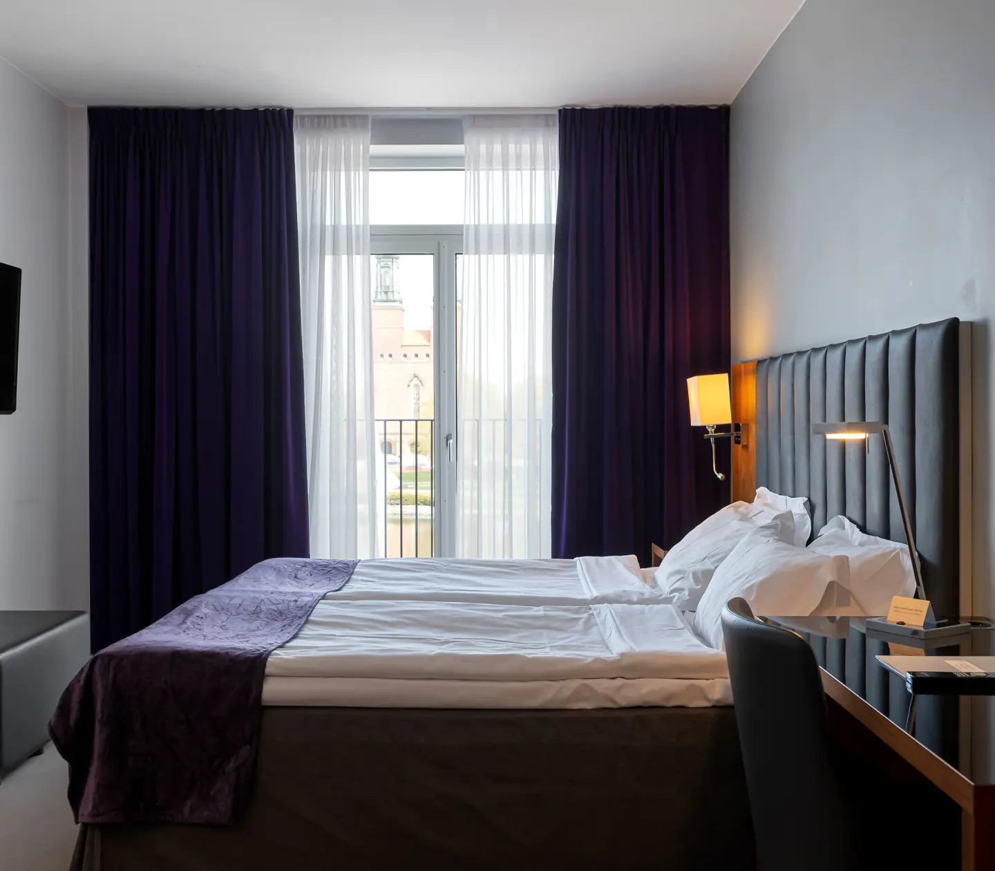 Hotellrum med dubbelsäng, fönster och tv