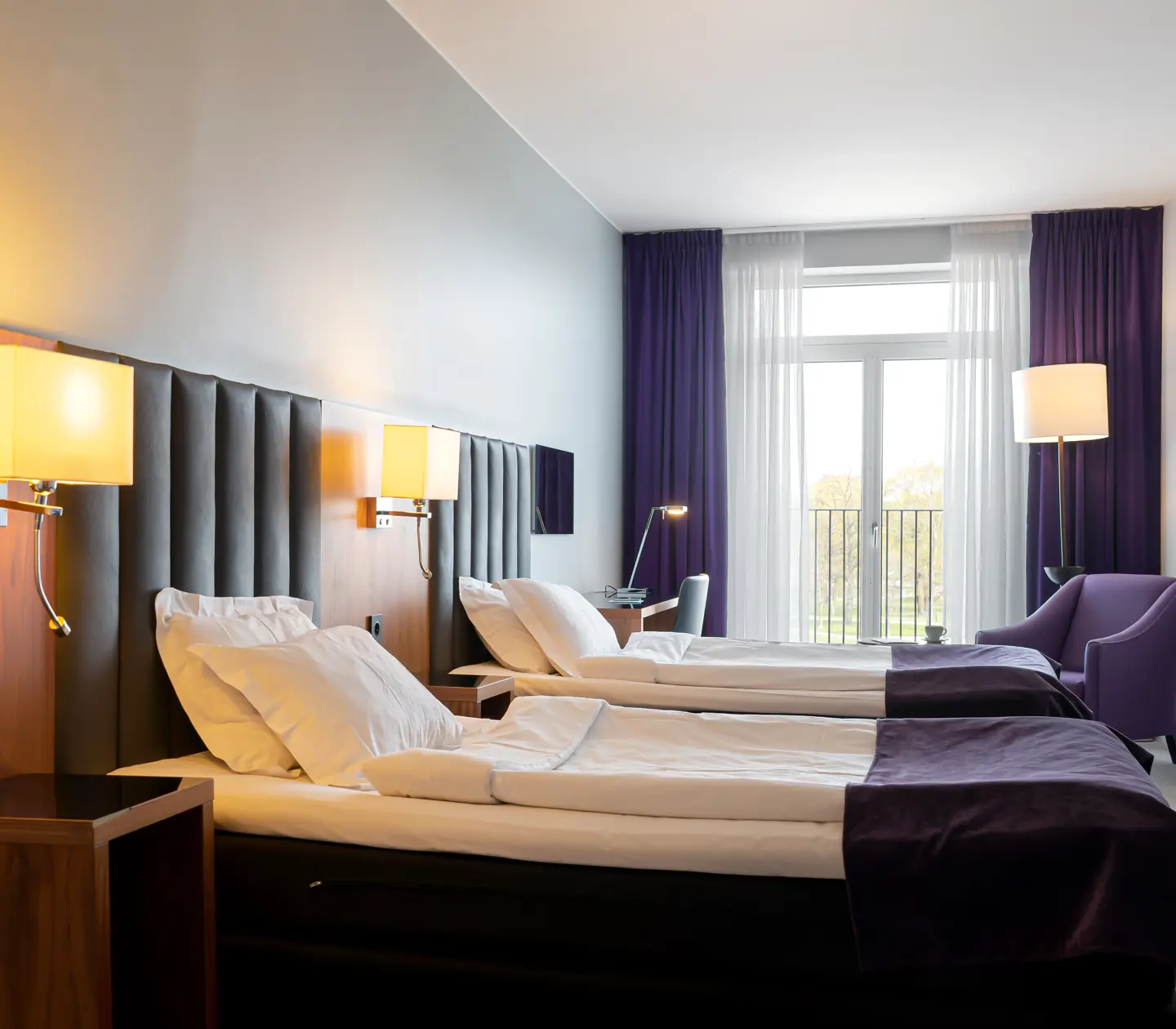Hotellrum med två enkelsängar, fåtölj och skrivbord