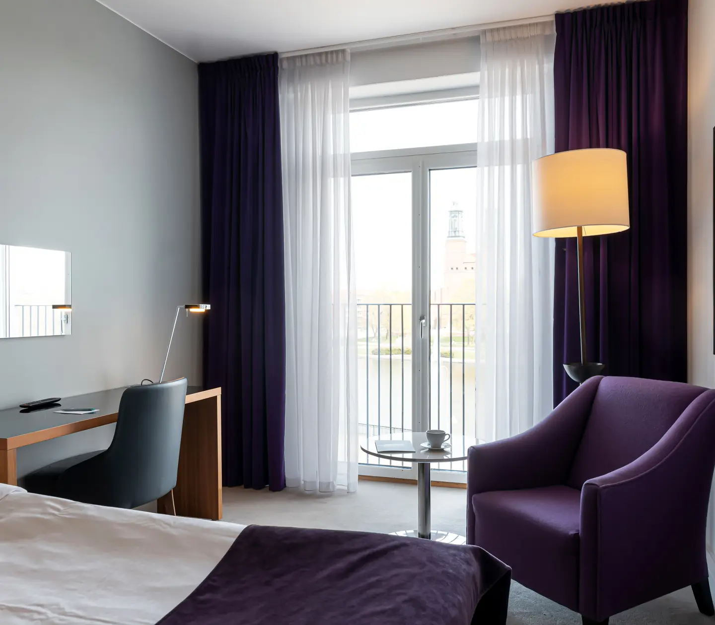 Hotellrum med fåtölj, skrivbord och stort fönster