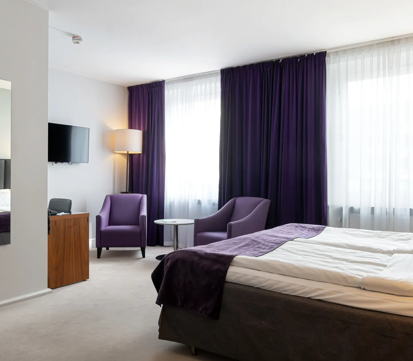 Hotellrum med dubbelsäng, fåtöljer och spegel