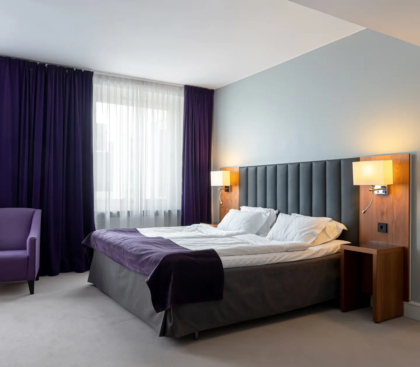 Hotellrum med dubbelsäng, fåtölj och fönster