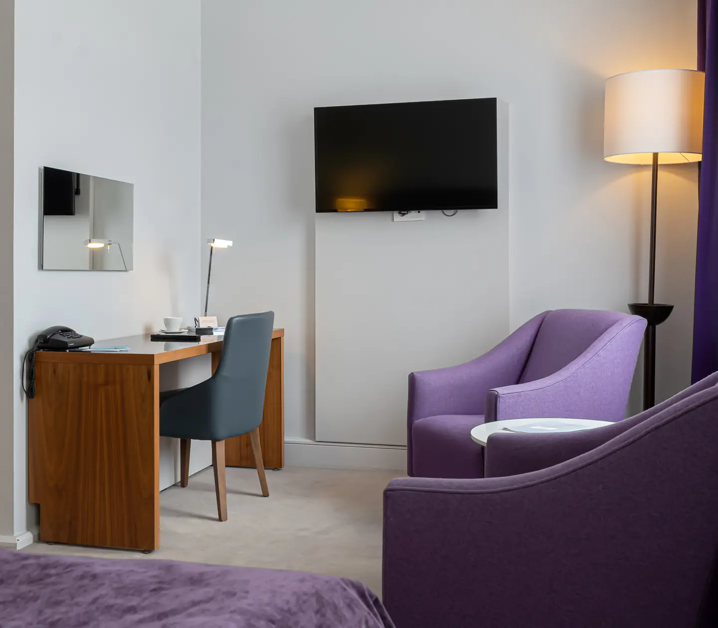 Hotellrum med fåtöljer, skrivbord och tv