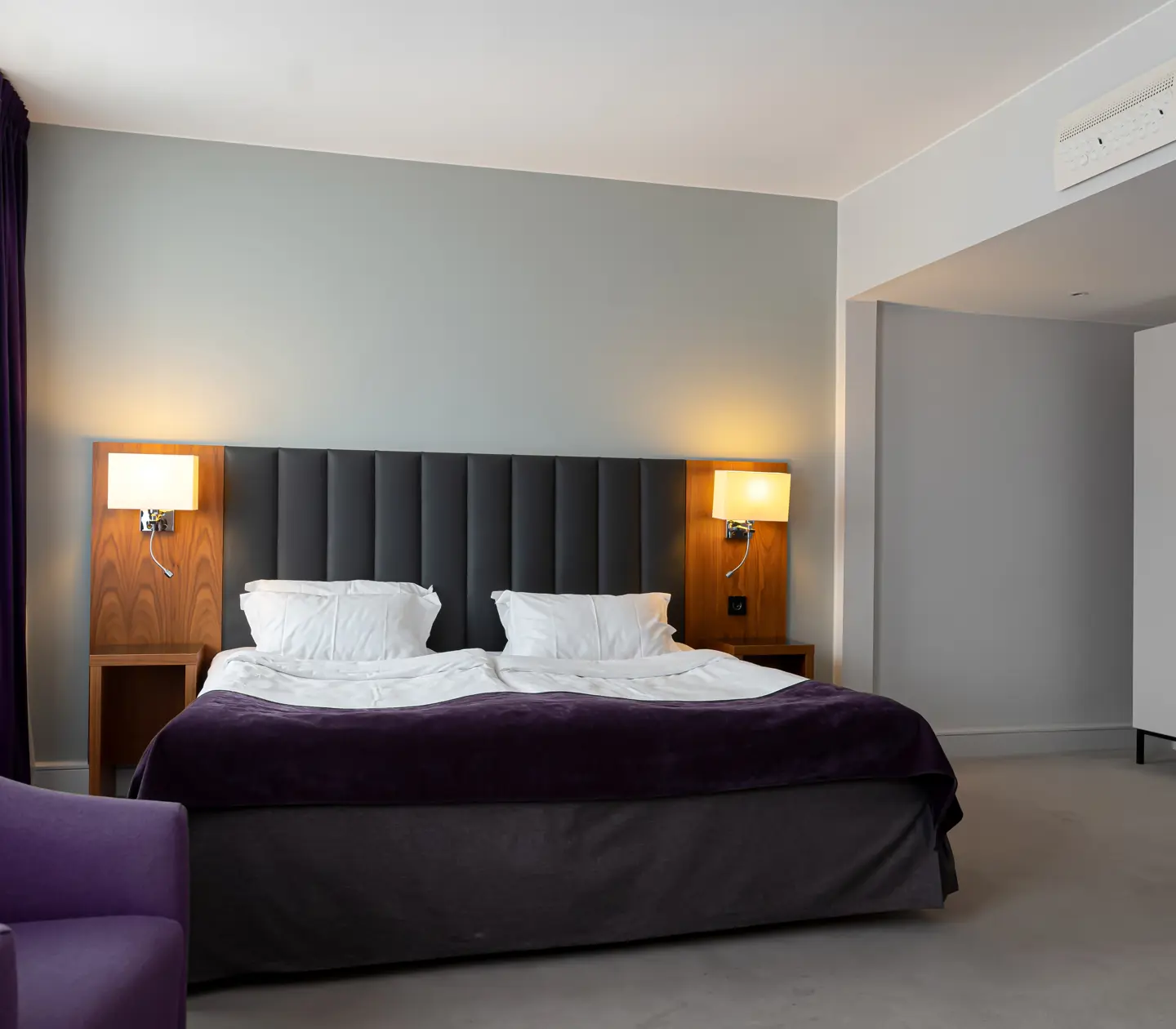 Hotellrum med dubbelsäng, fåtölj och garderob