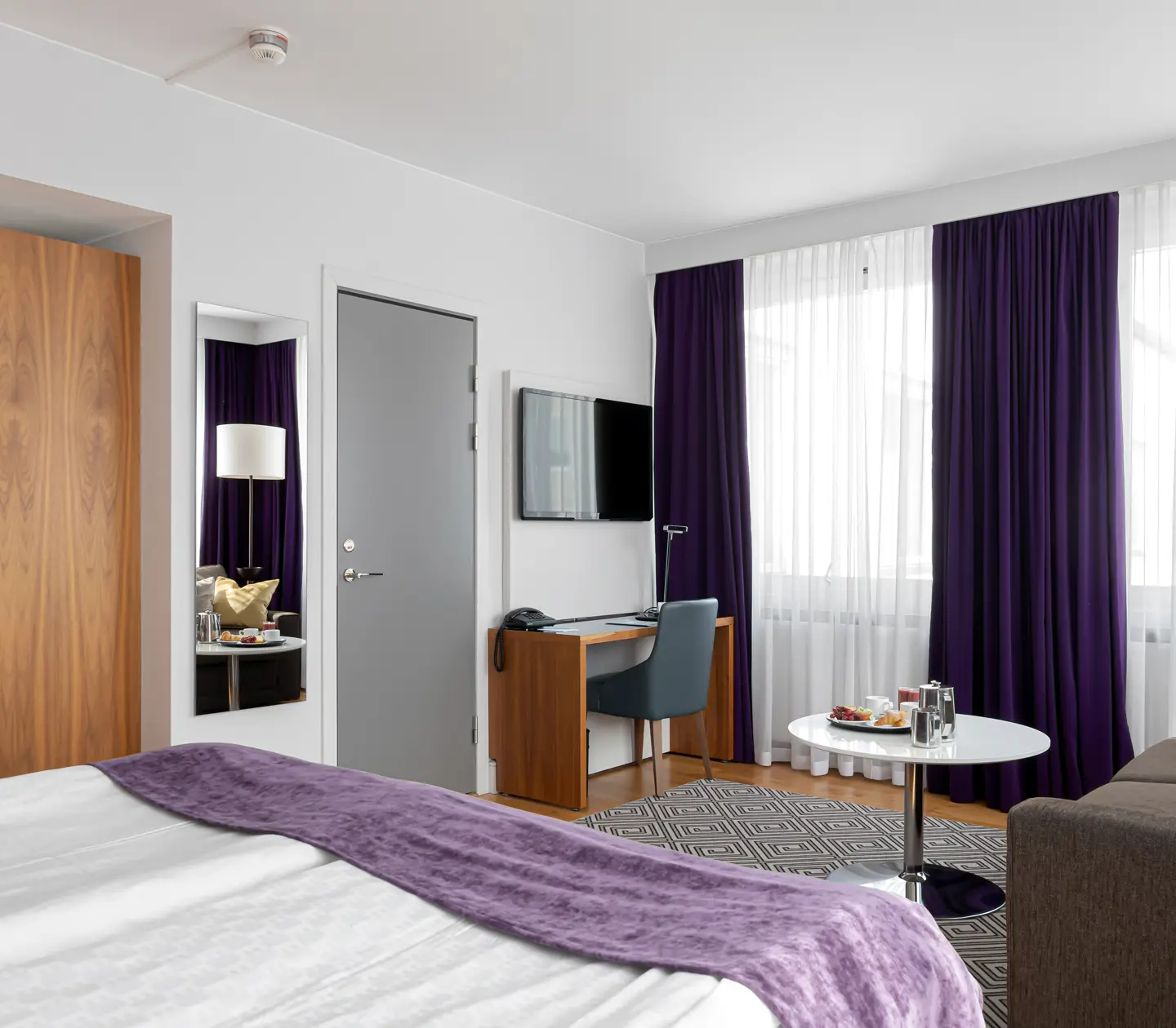 Hotellrum med soffa, skrivbord och spegel