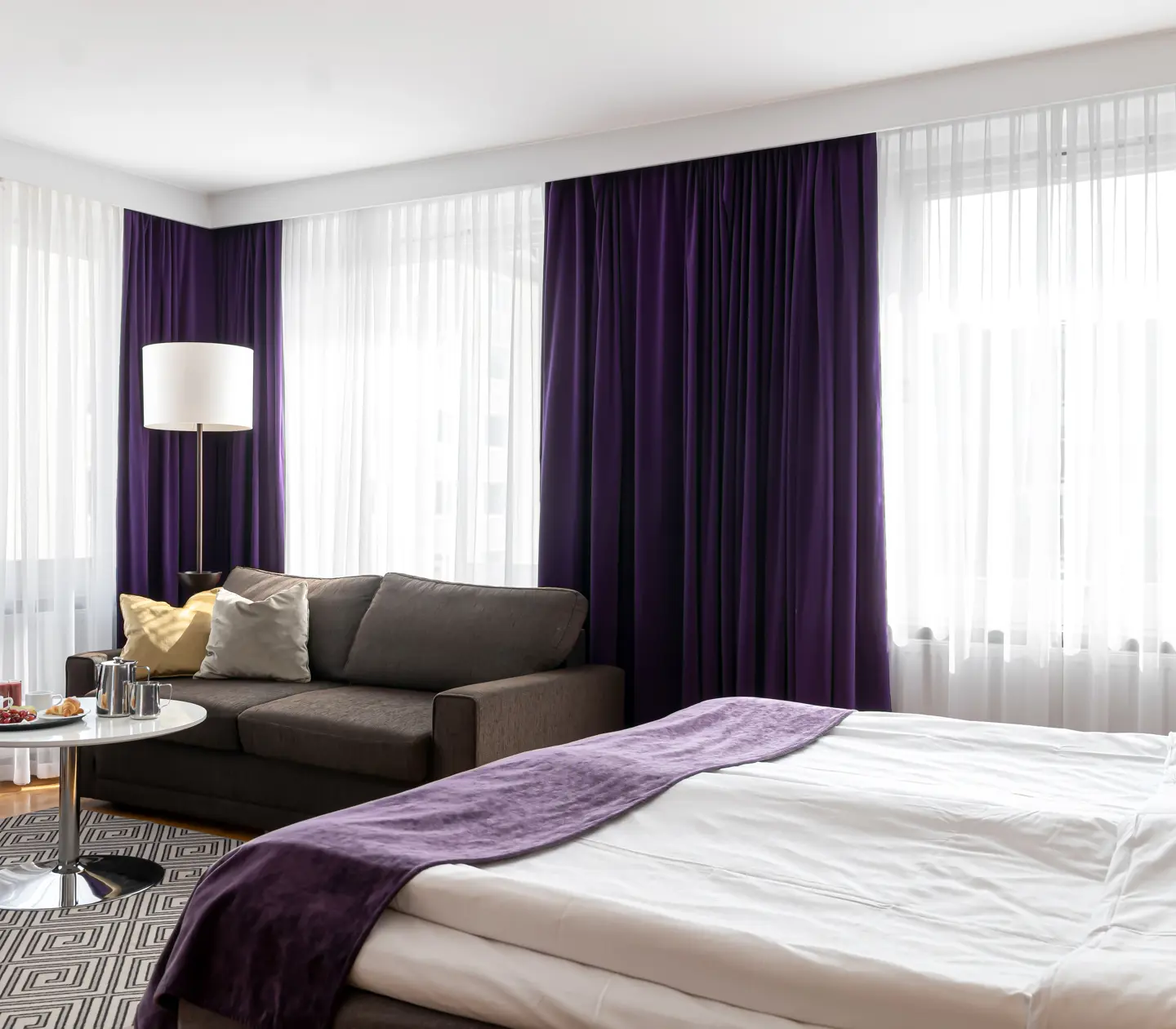 Hotellrum med säng, soffa och stora fönster