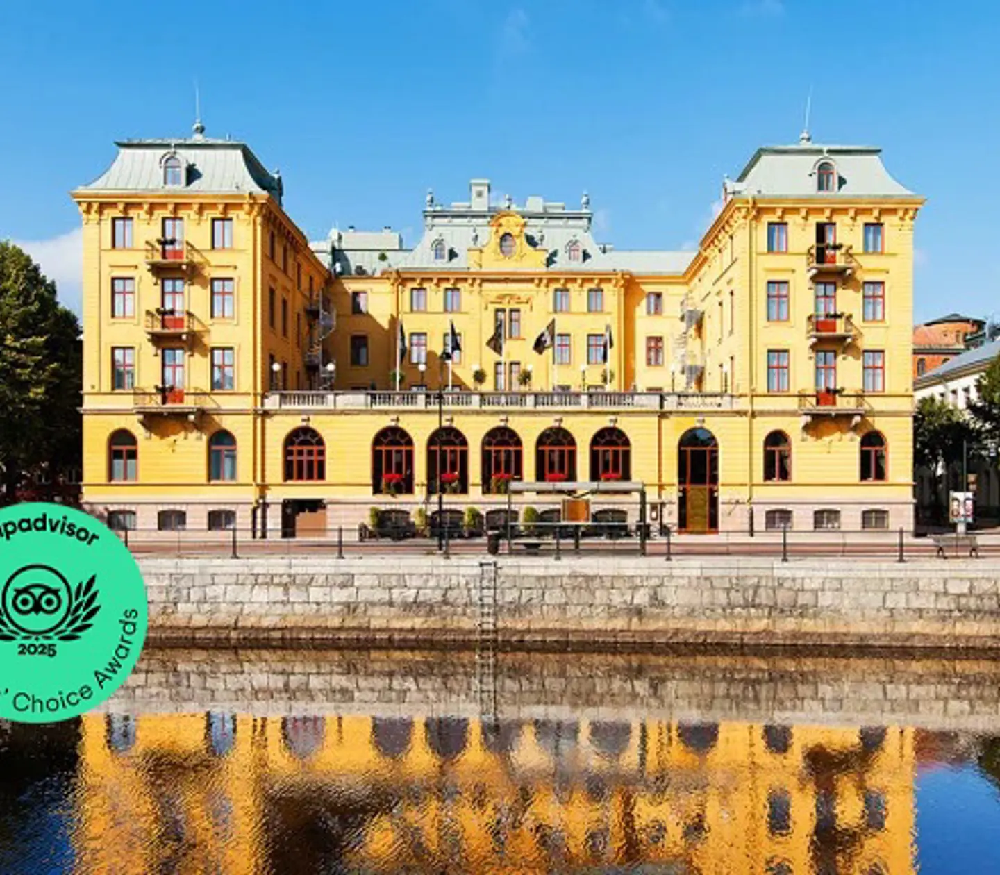 Gul byggnad med reflektion i vatten vid kaj i Sverige.