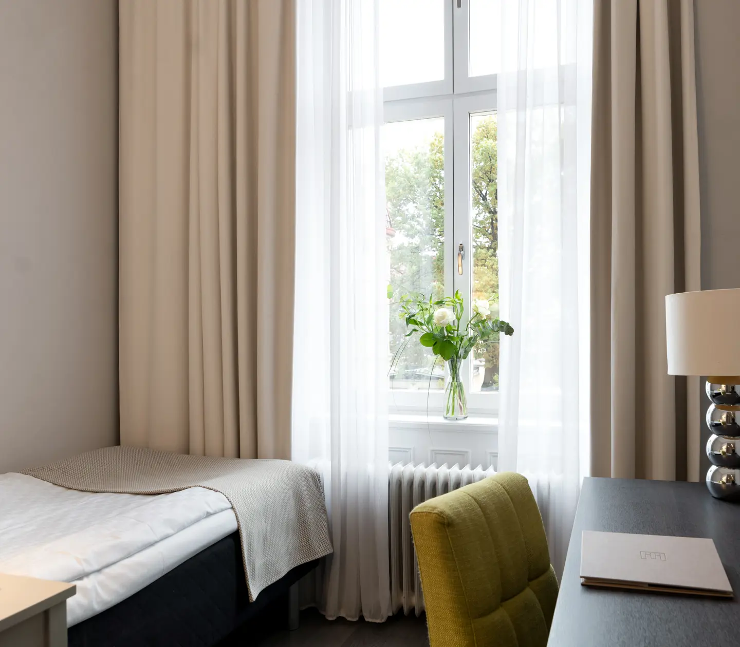Hotellrum med enkelsäng, skrivbord och fönster