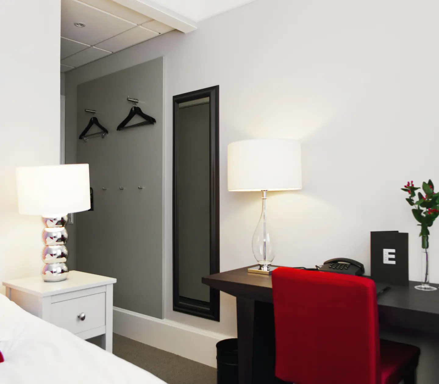 Hotellrum med skrivbord, bordslampa och spegel
