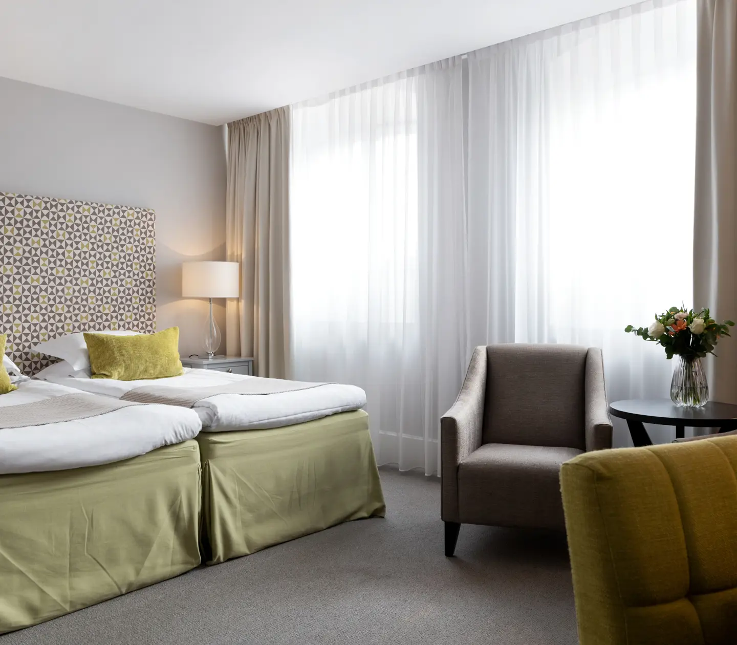 Hotellrum med säng, fönster och fåtöljer