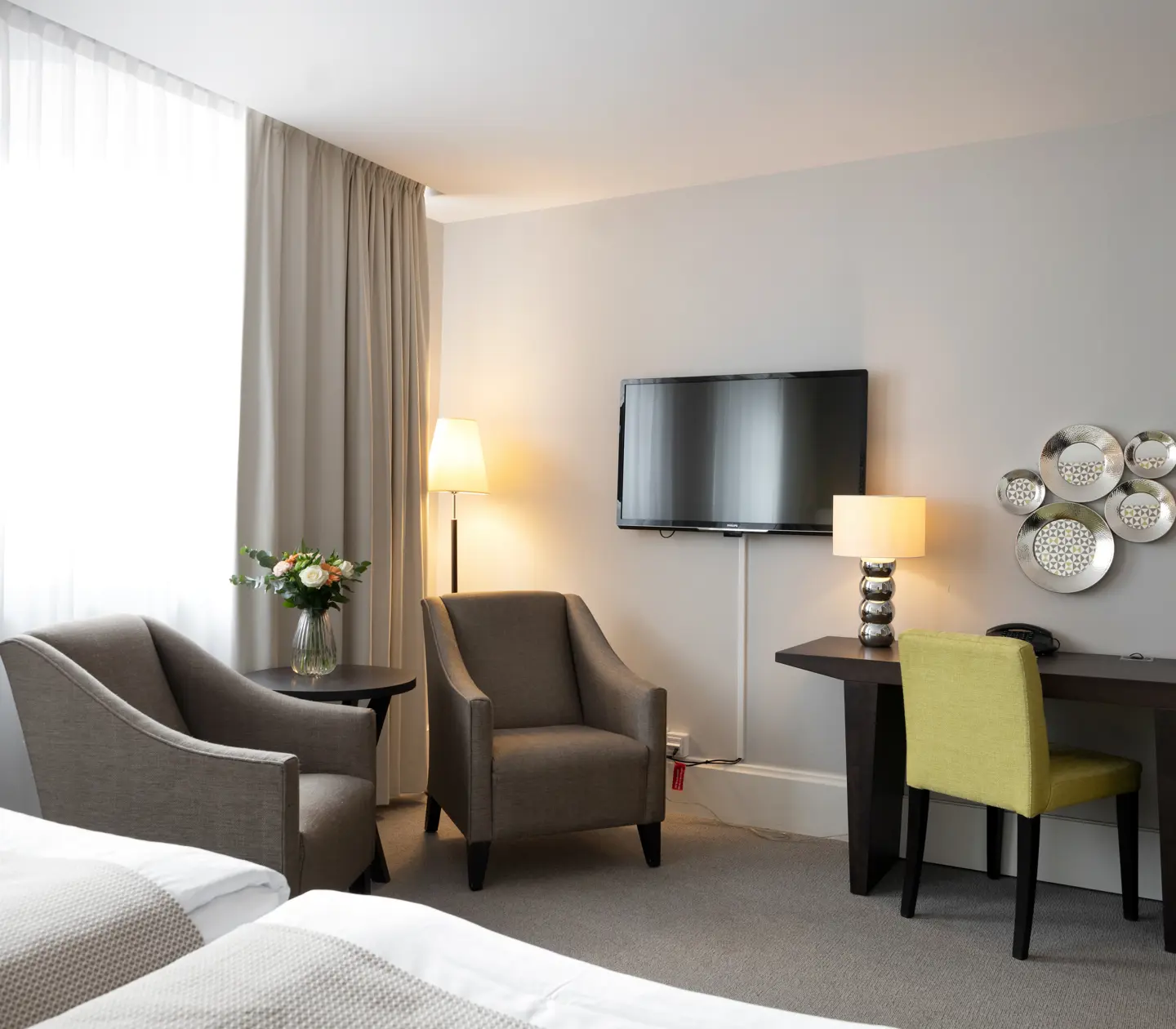 Hotellrum med skrivbord, fåtöljer och tv