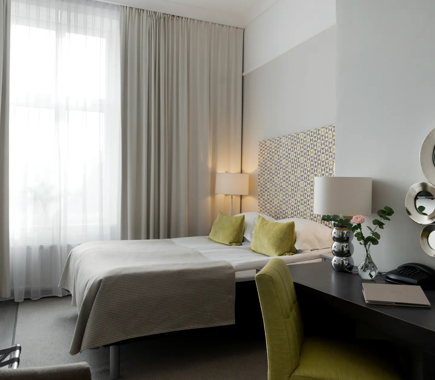 Hotellrum med dubbelsäng, skrivbord och fönster