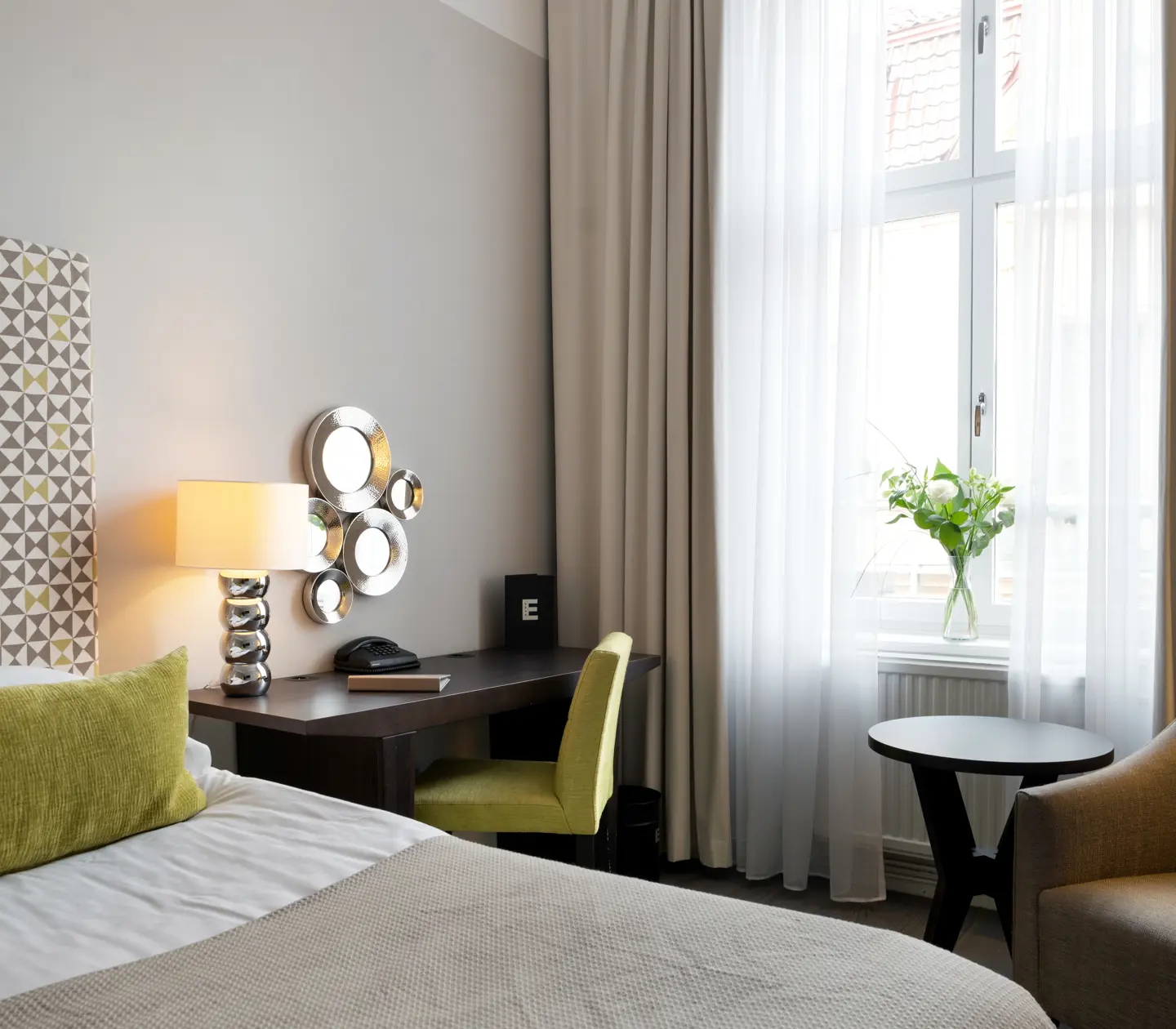 Hotellrum med säng, skrivbord och fåtölj