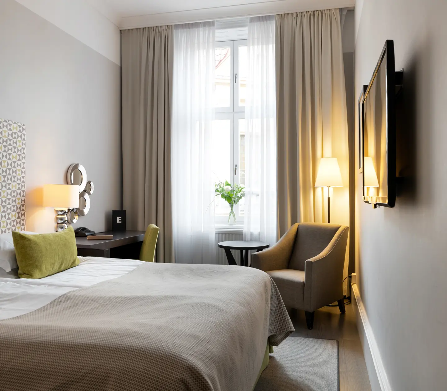 Hotellrum med säng, fåtölj och skrivbord