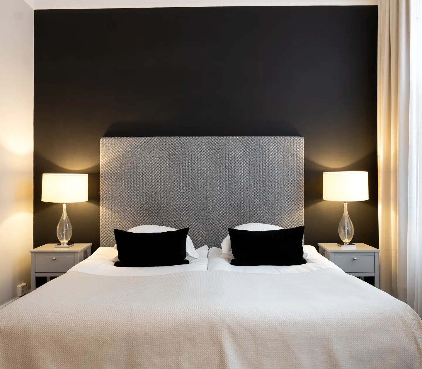 Hotellrum med svart vägg, säng och sänglampor