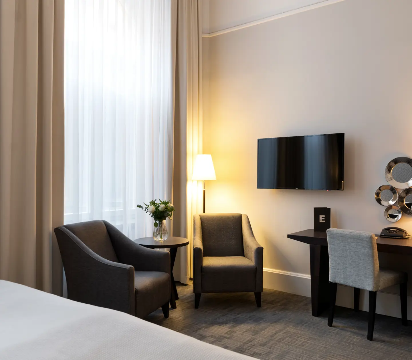 Hotellrum med skrivbord, fåtöljer och tv