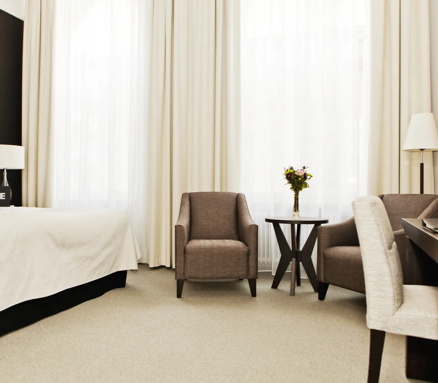 Hotellrum med skrivbord, fåtöljer och fönster