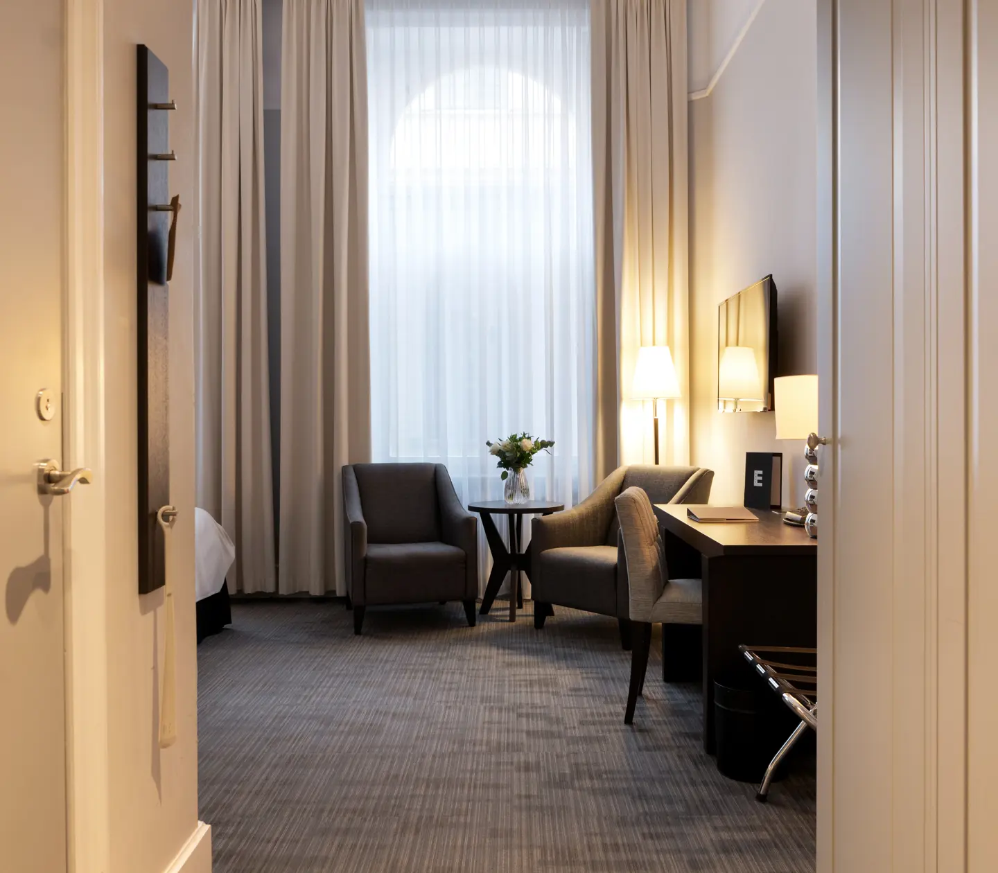 Hotellrum med garderob, skrivbord och fåtöljer
