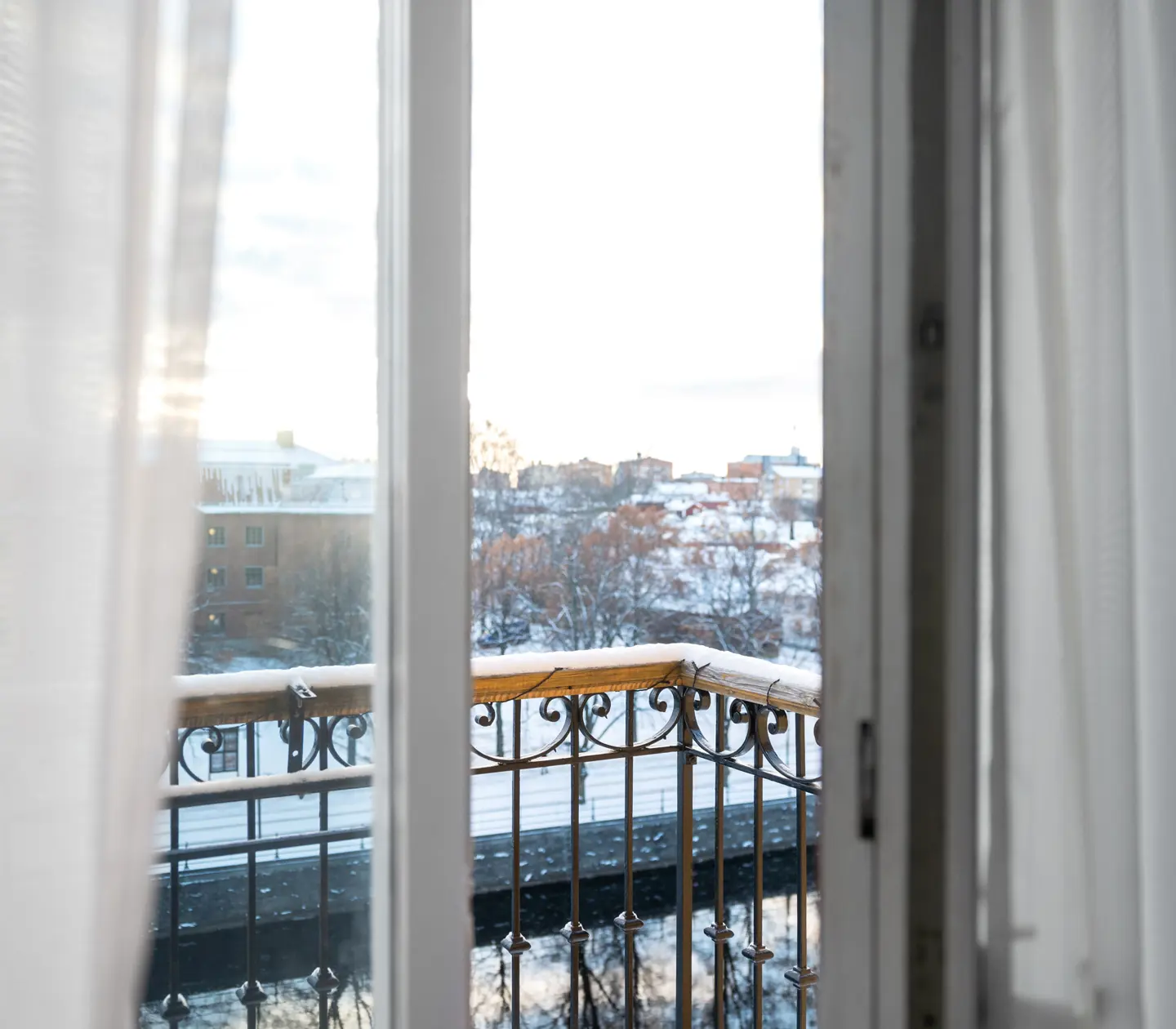Balkongdörr på glänt mot ett vintrigt Gävle