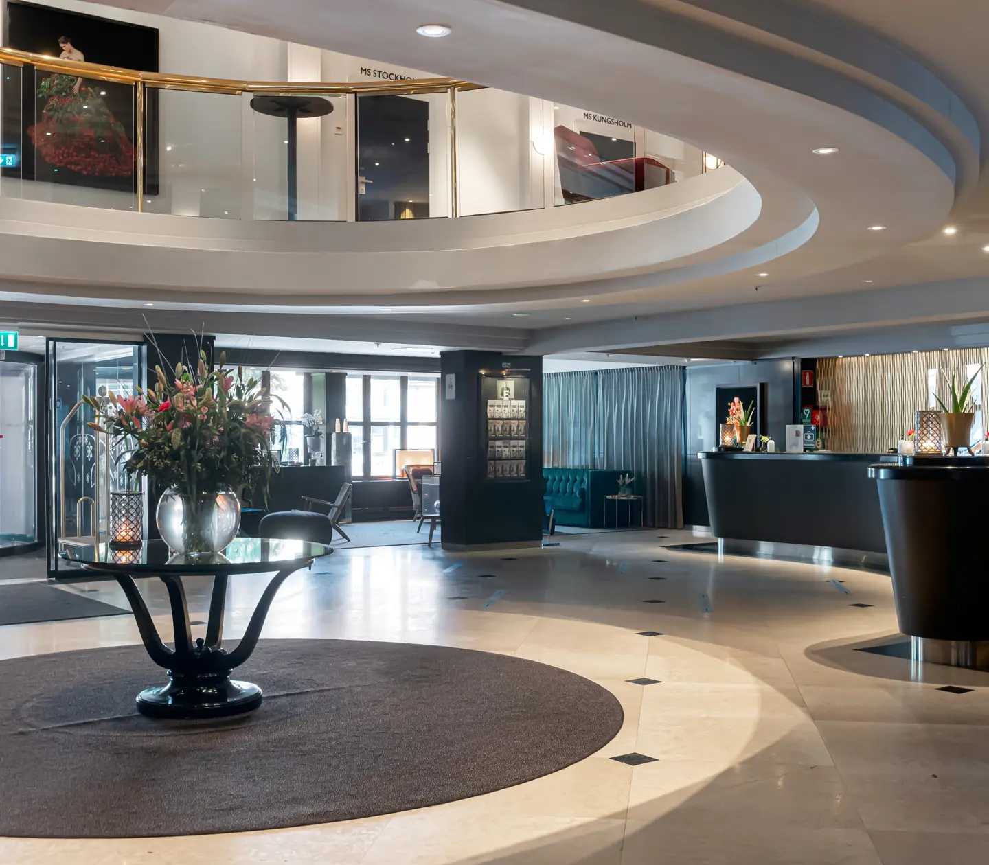 Hotellobby med receptionsdiskar och öppet tak