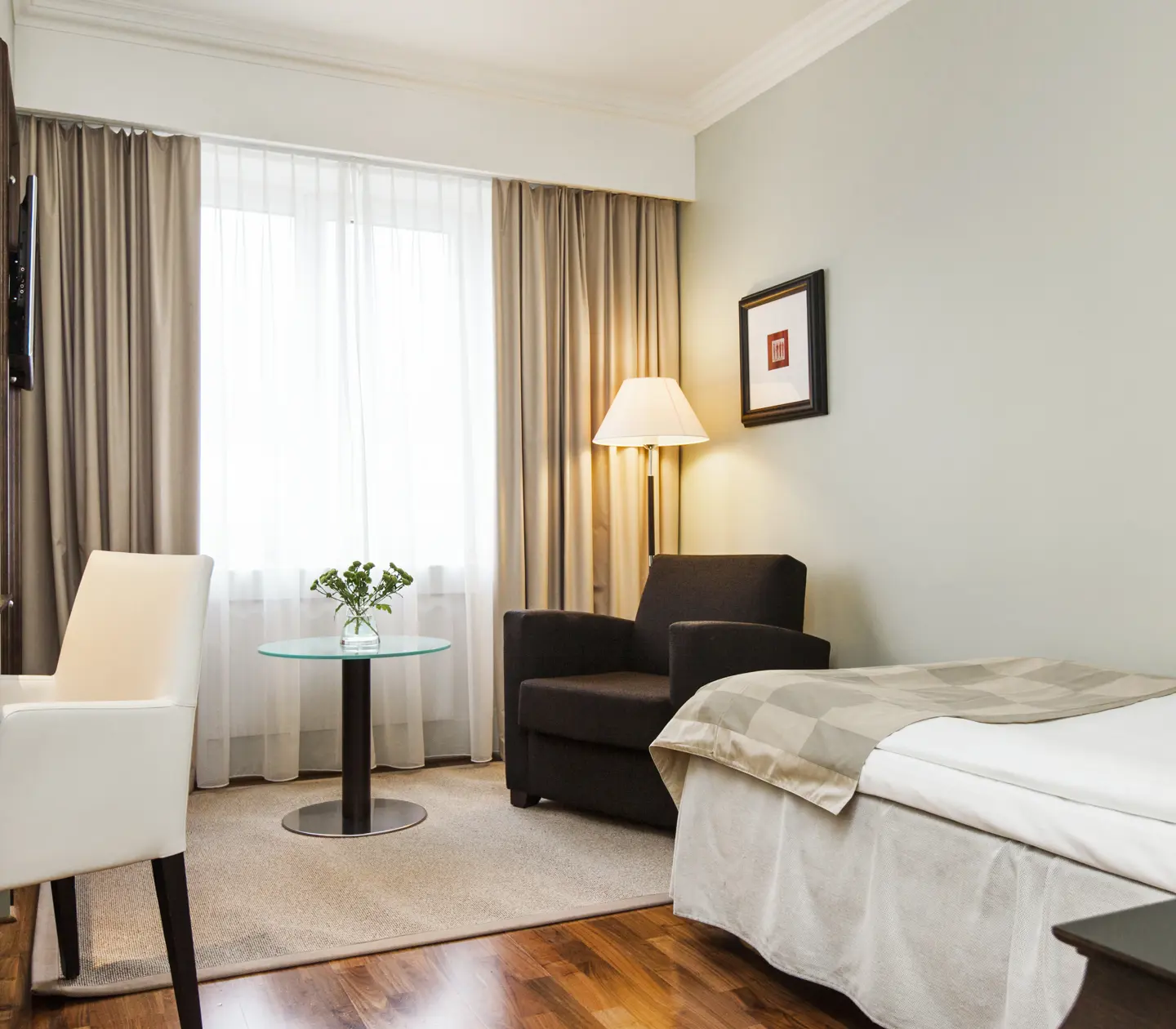 Mysigt hotellrum med enkelsäng, fåtölj och skrivbord
