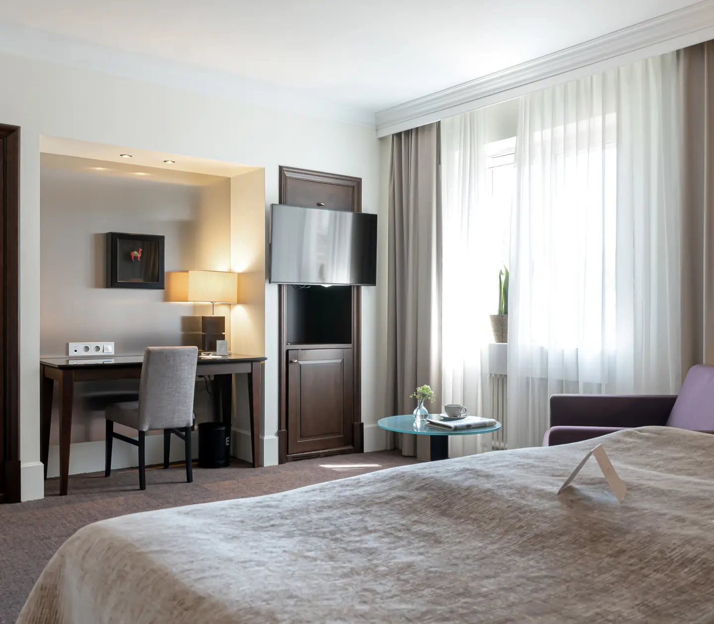 Hotellrum med fåtölj, skrivbord och tv