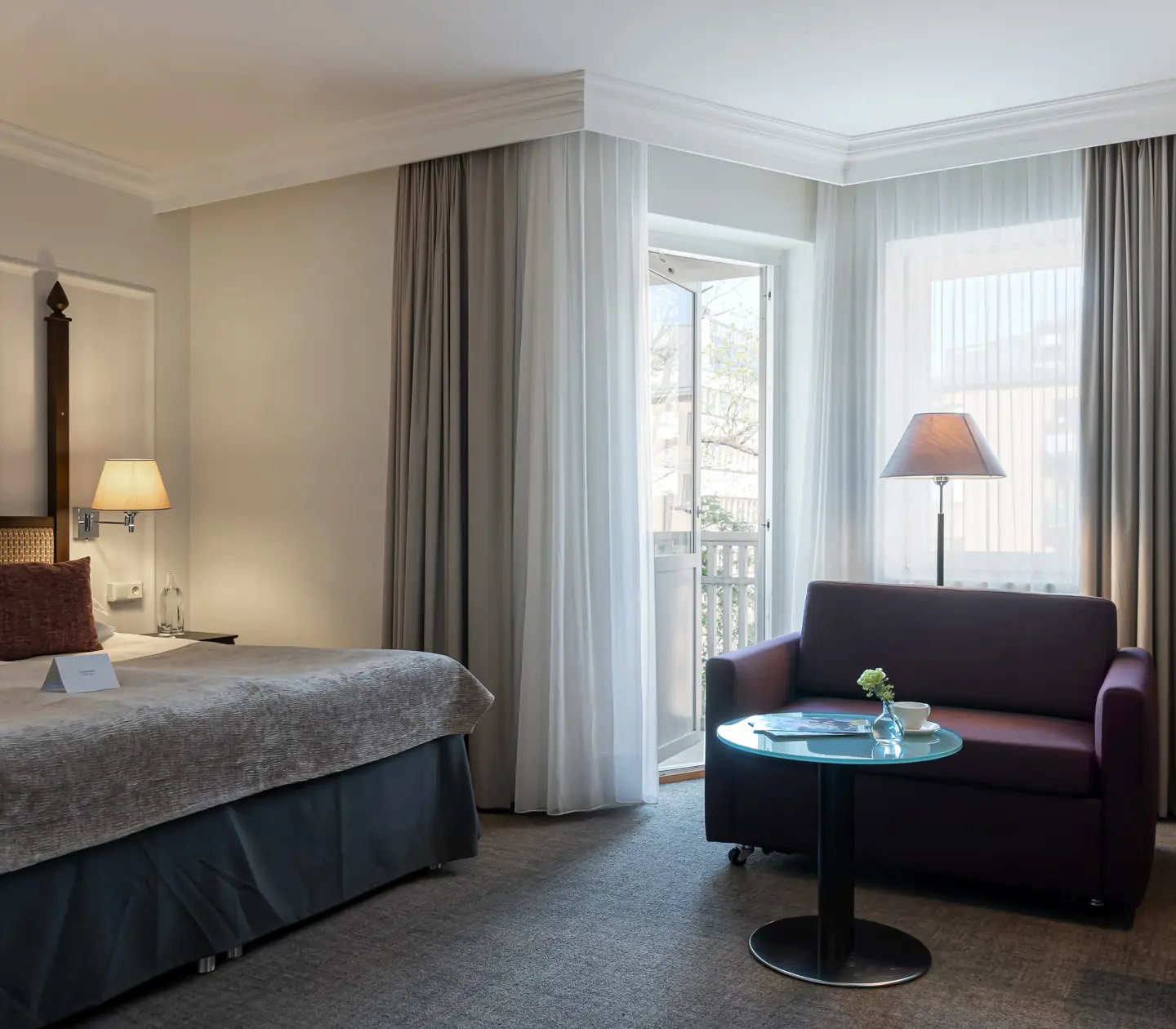 Hotellrum med dubbelsäng, soffa och balkongdörr