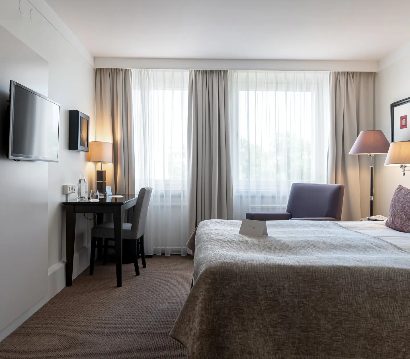 Hotellrum med dubbelsäng, skrivbord och fönster