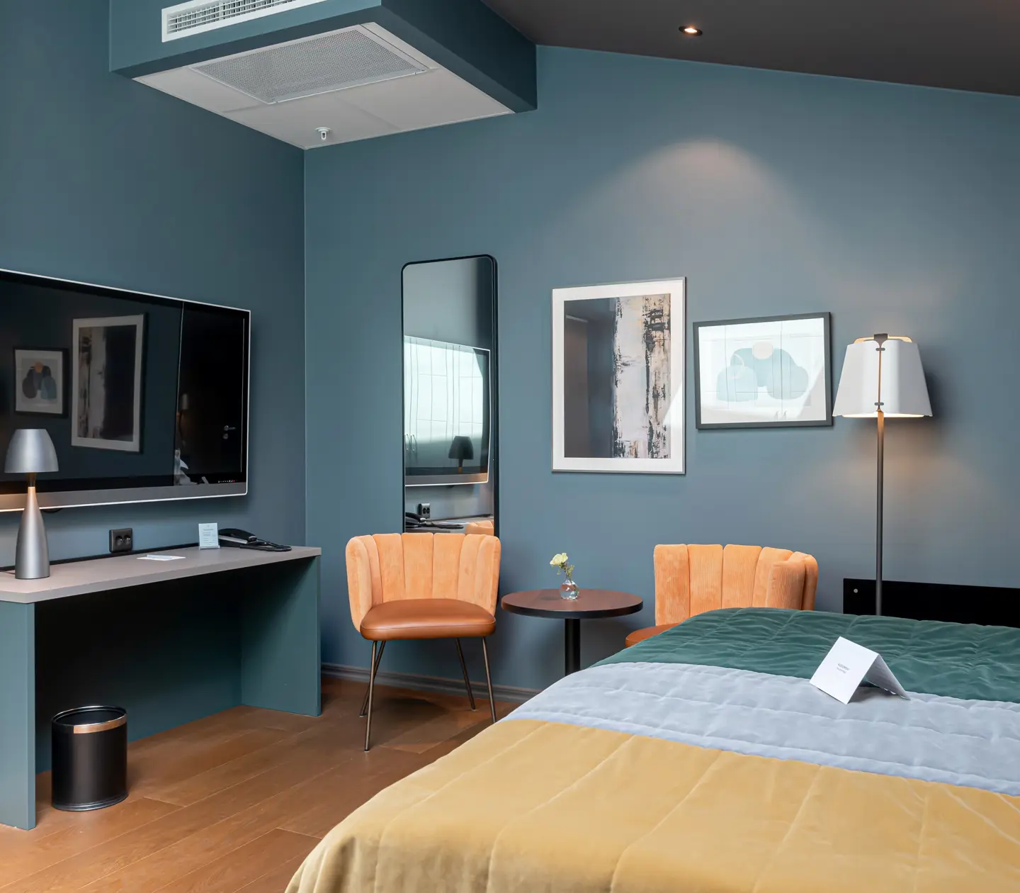 Färgglatt hotellrum med dubbelsäng, fåtöljer och tv