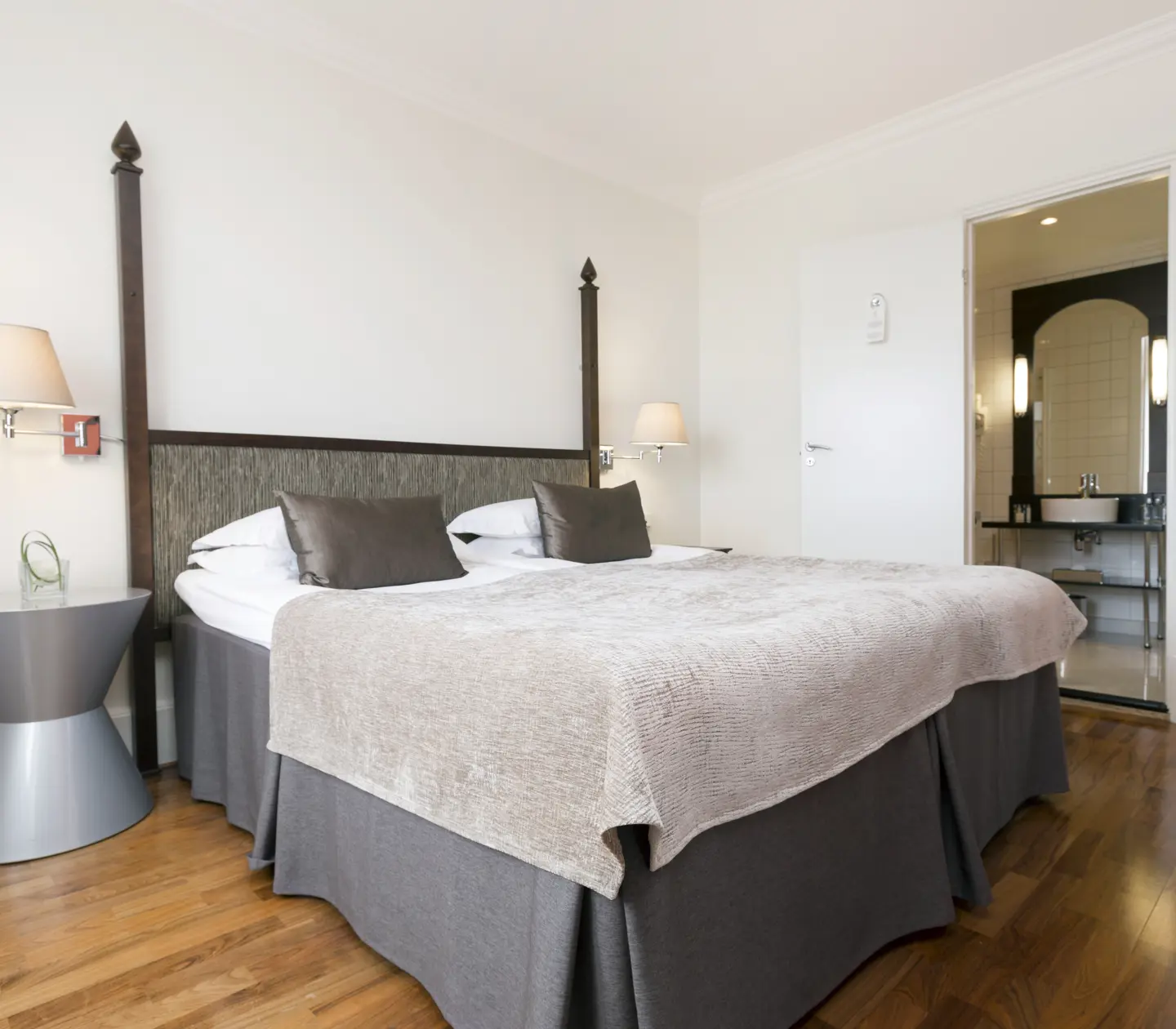 Hotellrum med dubbelsäng, sänglampor och dörr in till badrum