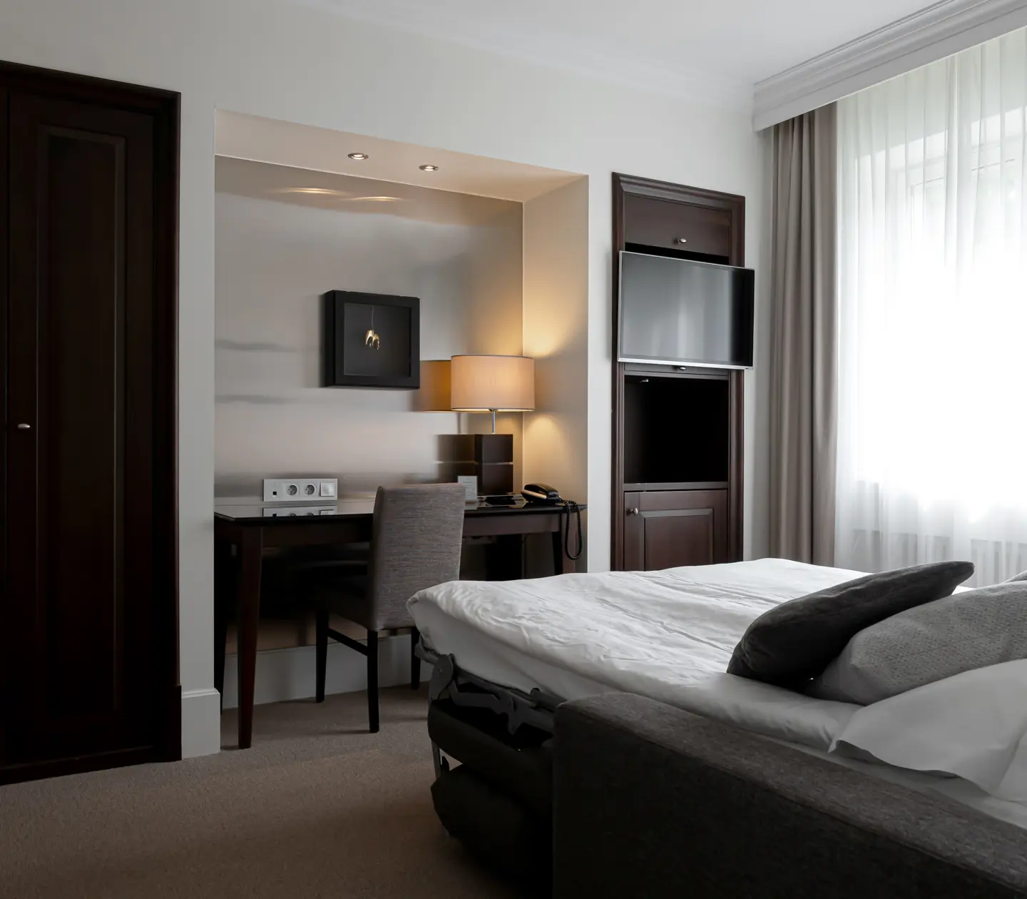 Hotellrum med dubbelsäng, skrivbord och tv