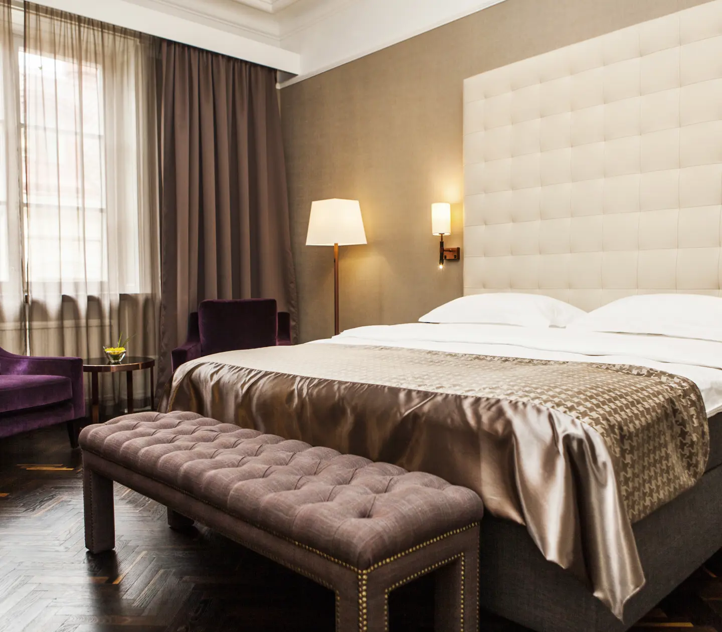Hotellrum med dubbelsäng, stor sänggavel och fåtölj