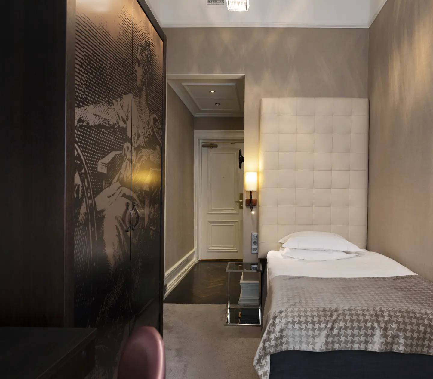 Litet hotellrum med säng och garderob