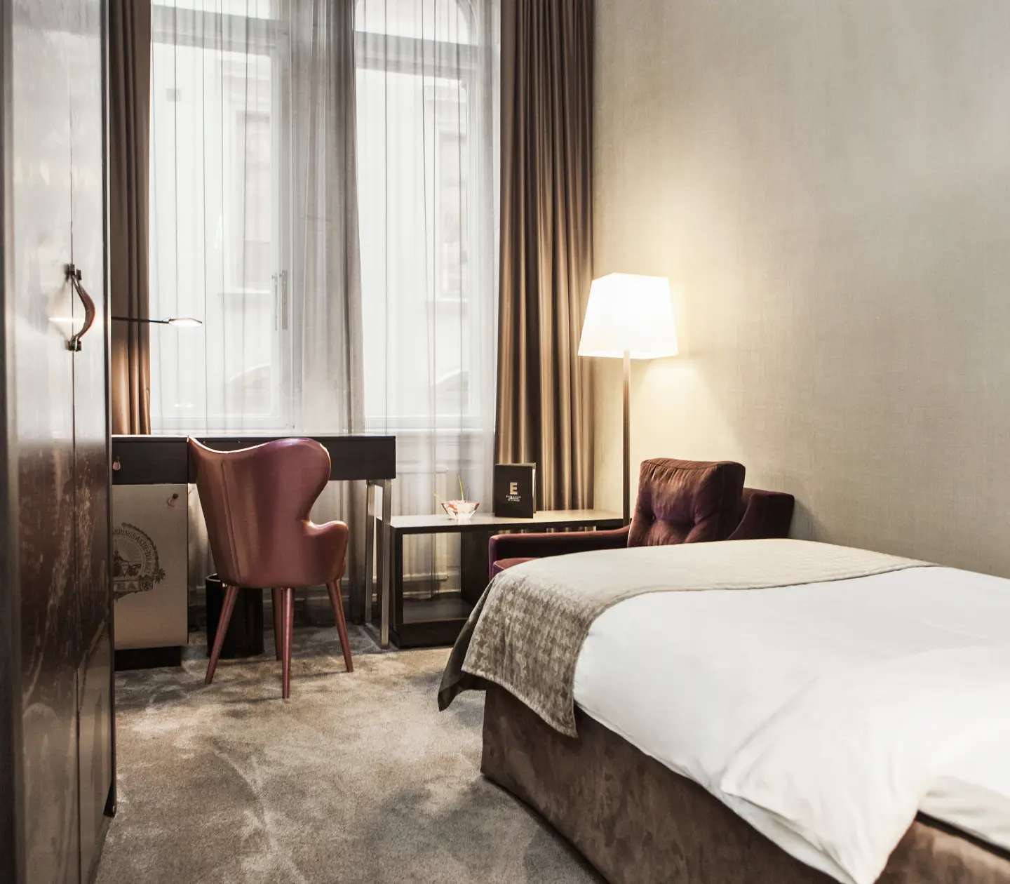 Mysigt hotellrum med enkelsäng, skrivbord och stora fönster