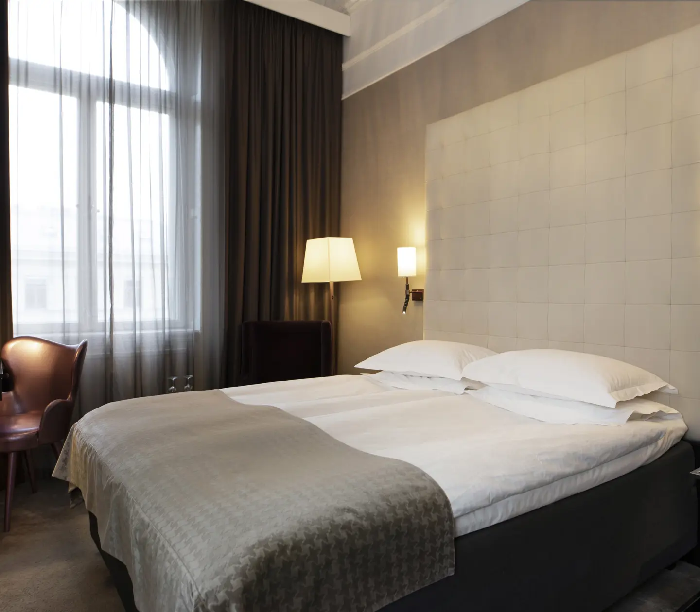 Hotellrum med säng, stor sänggavel och skrivbord