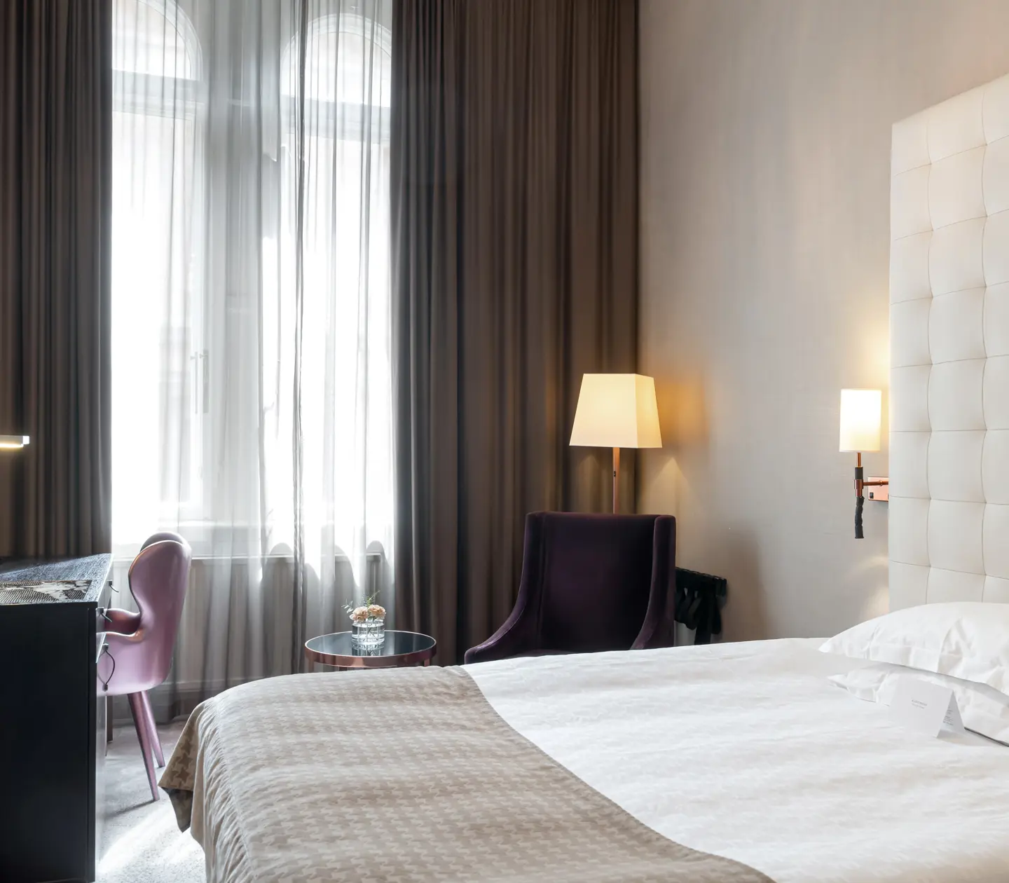 Ljust hotellrum med säng, stor sänggavel och skrivbord