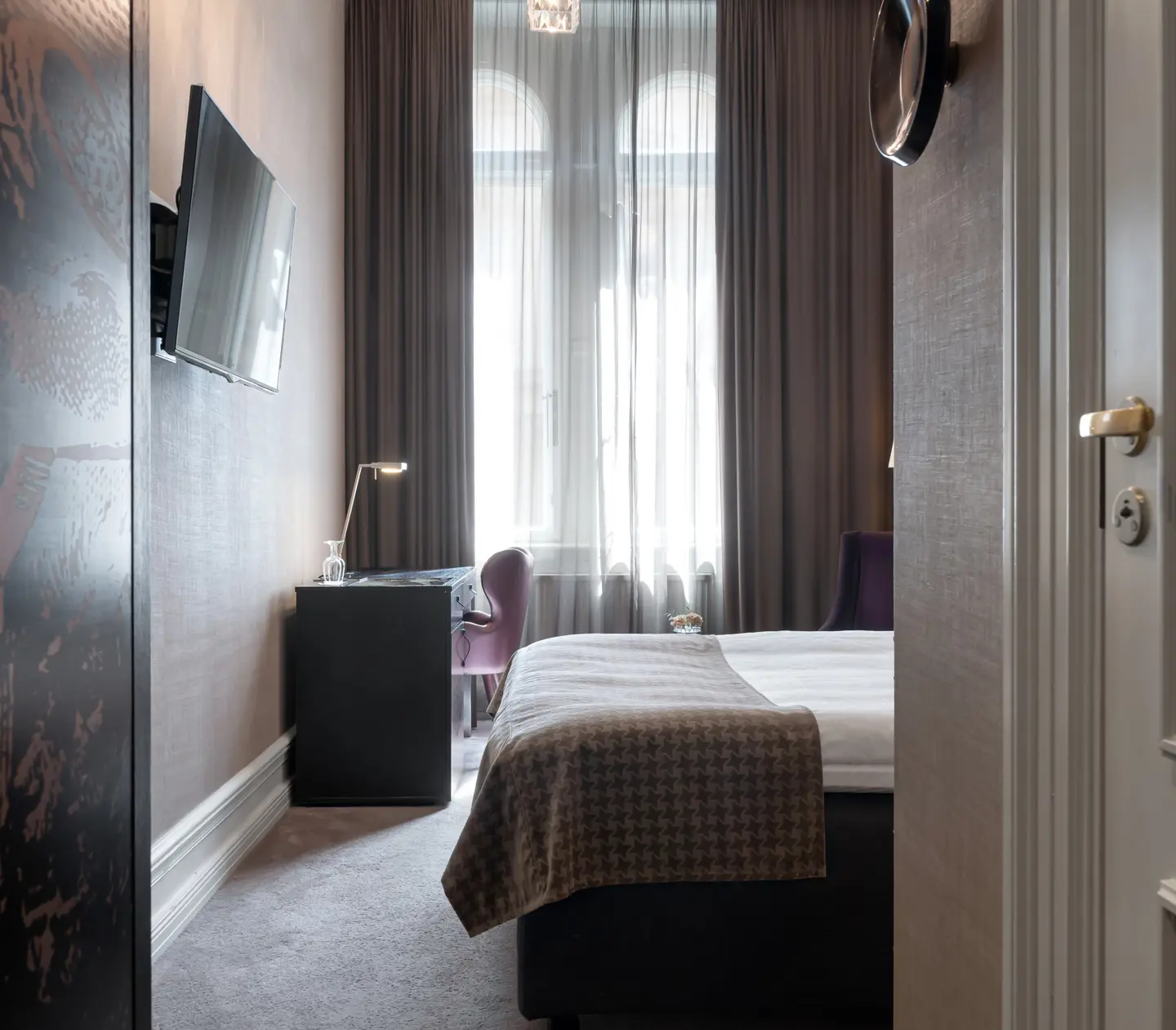 Hotellrum med säng, skrivbord och stort fönster