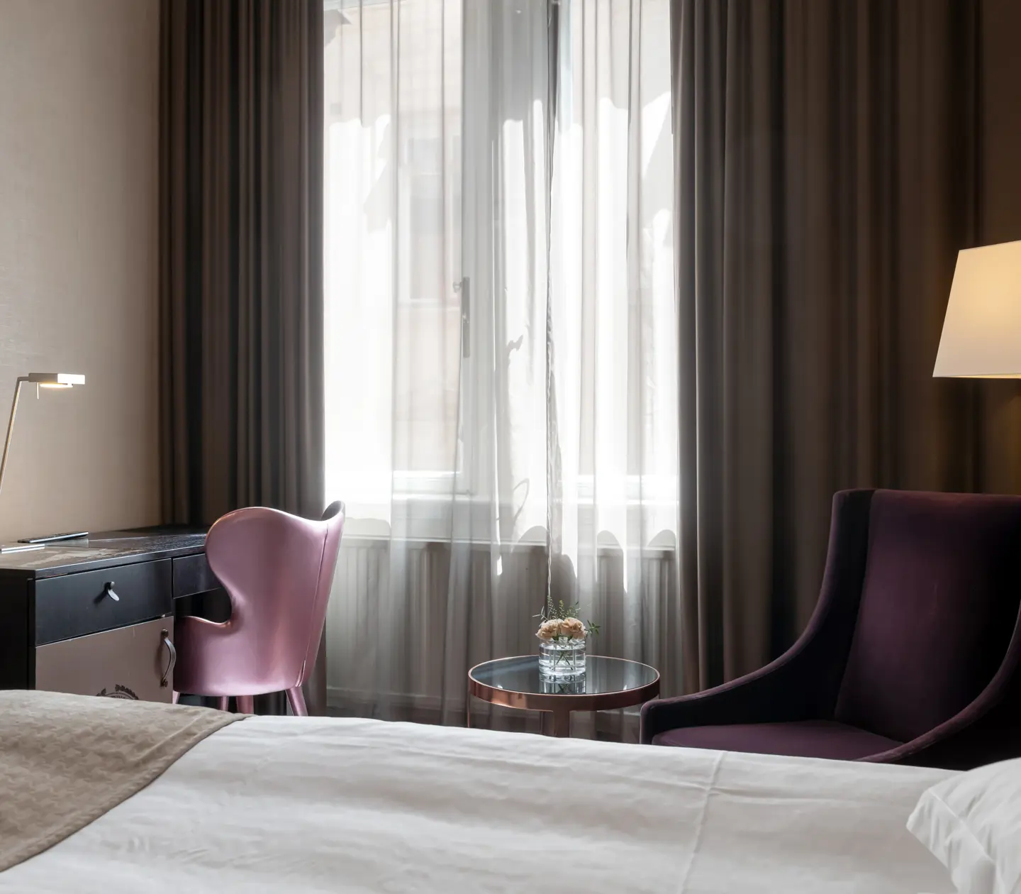 Hotellrum med fåtölj, skrivbord och fönster