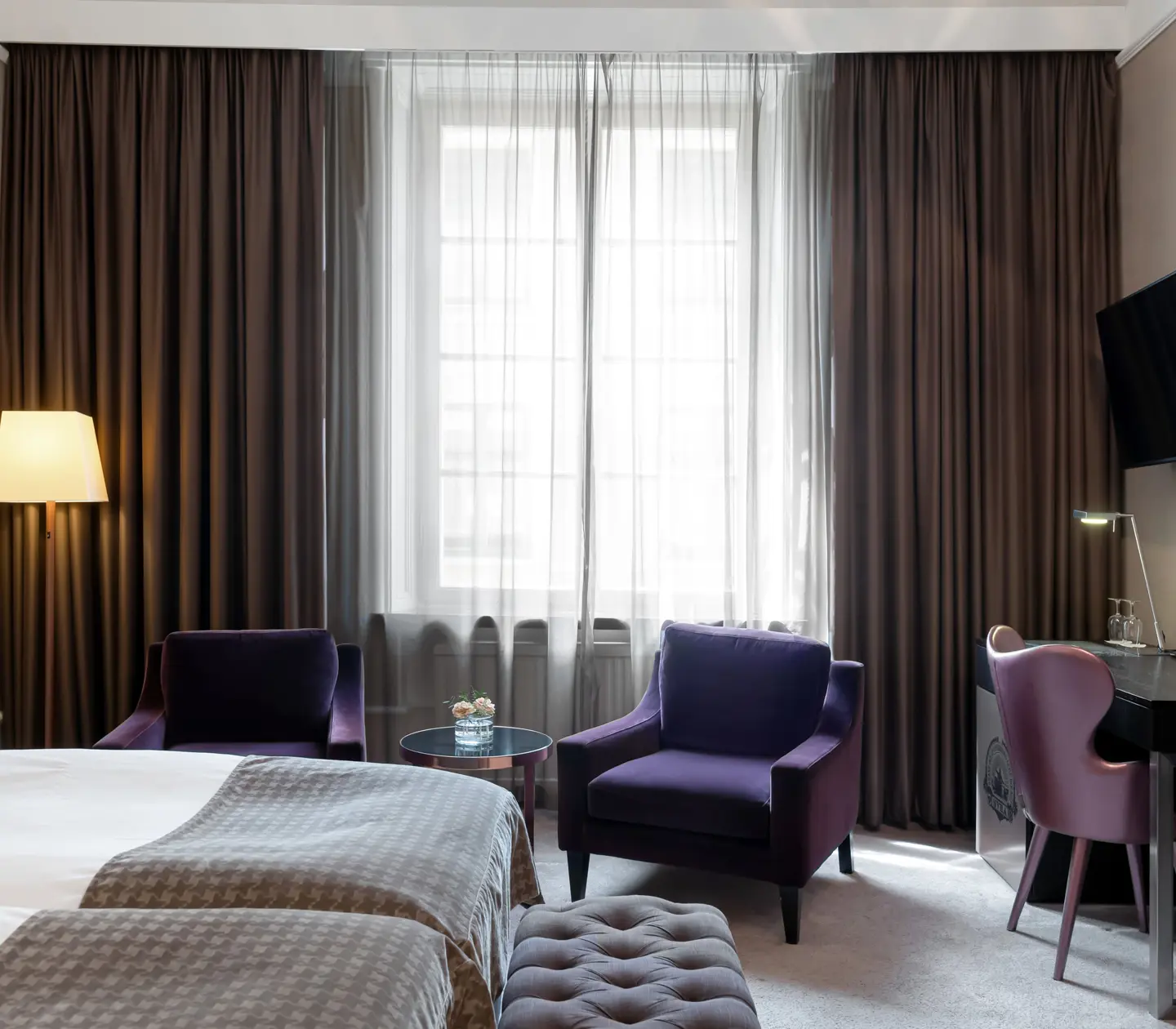Hotellrum med säng, fåtöljer och skrivbord