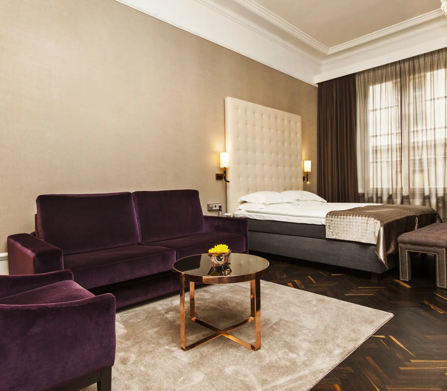 Hotellrum med säng, stor sänggavel och soffa