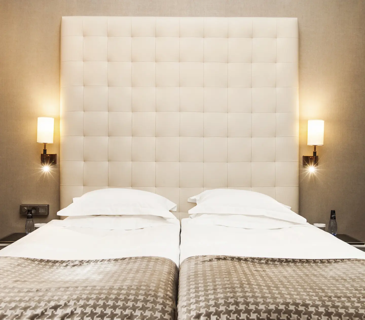 Hotellrum med säng, stor sänggavel och sänglampor