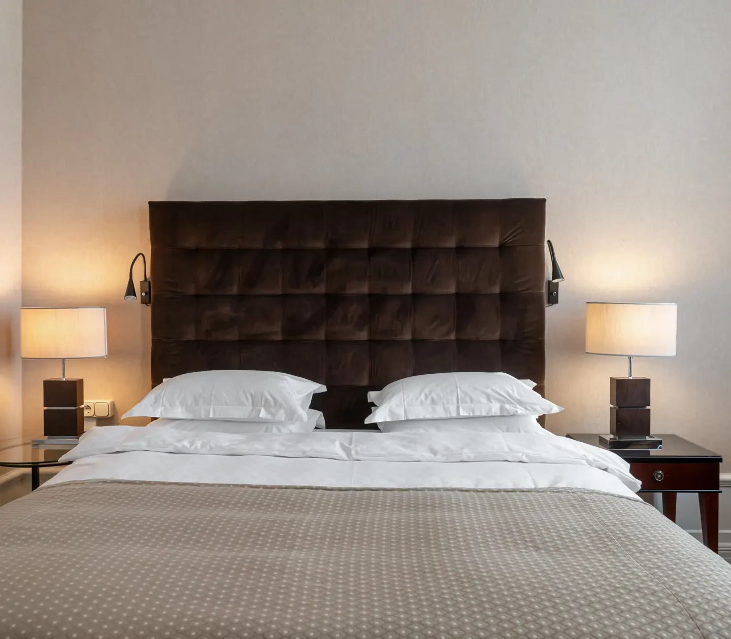 Hotellrum med säng, stor sänggavel och sänglampor