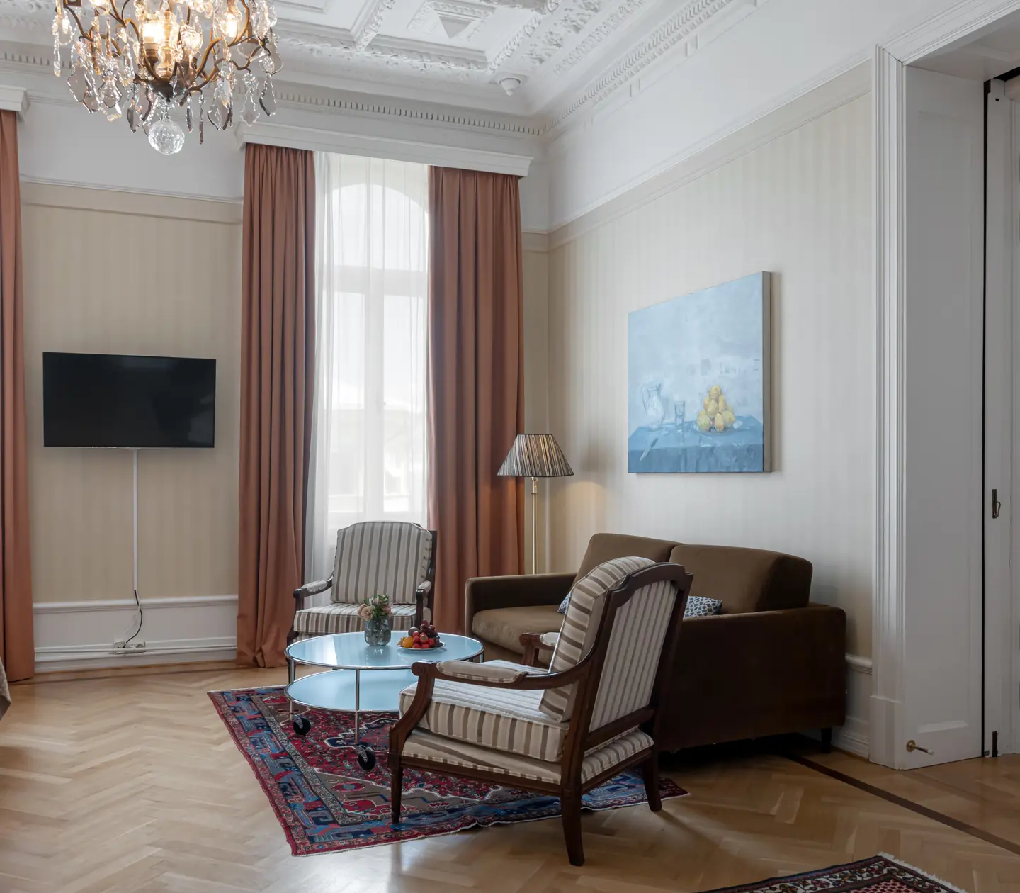 Charmigt hotellrum med stora fönster, soffgrupp och tv