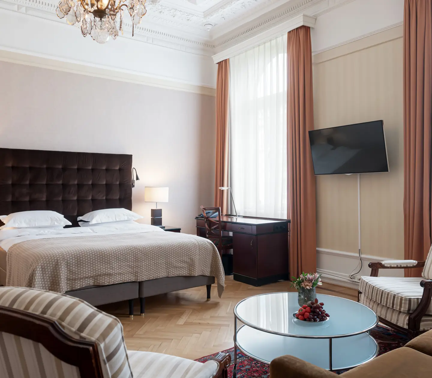 Charmigt hotellrum med säng, stora fönster och skrivbord