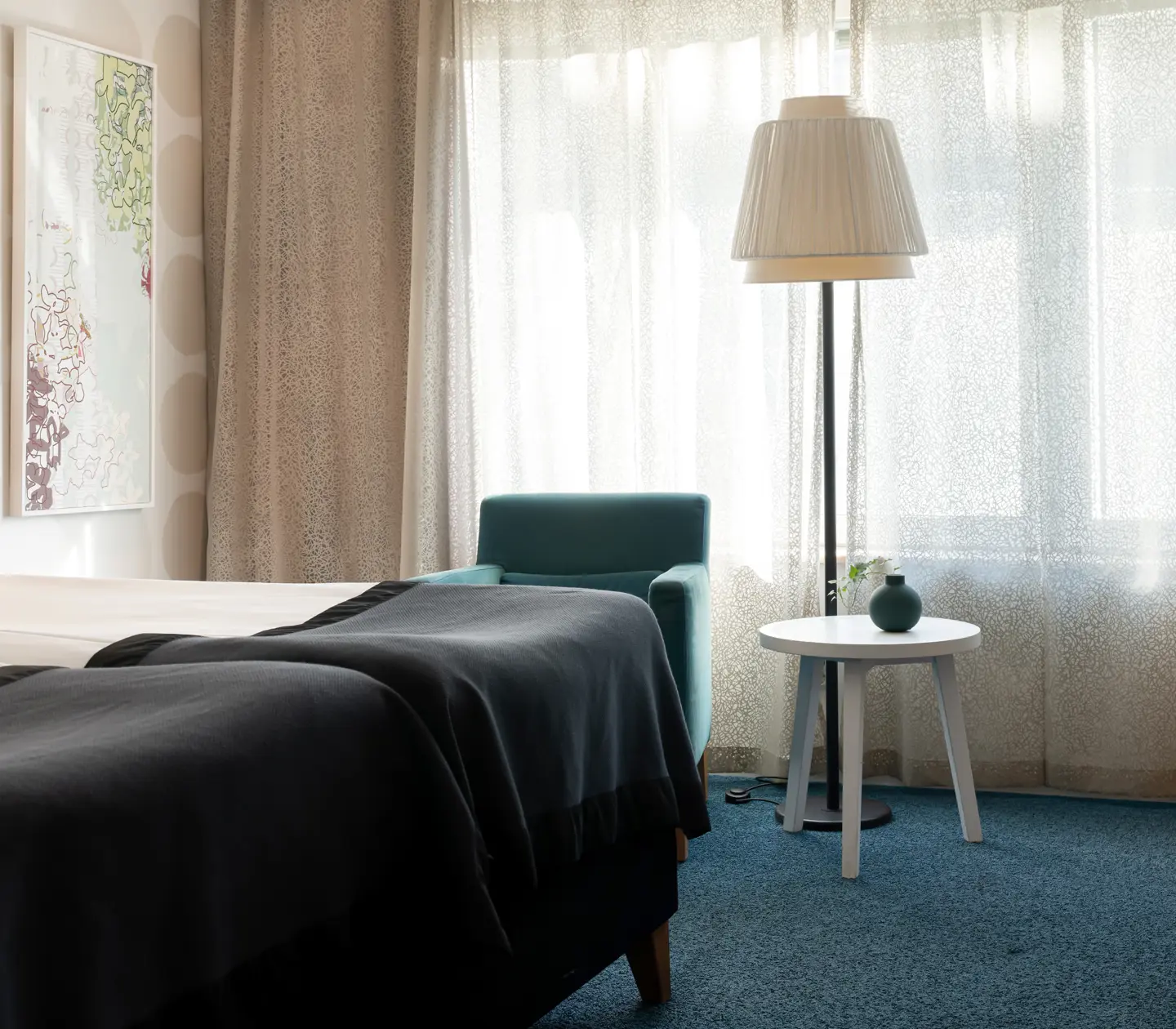 Mysigt hotellrum med säng, skrivbord och fåtölj