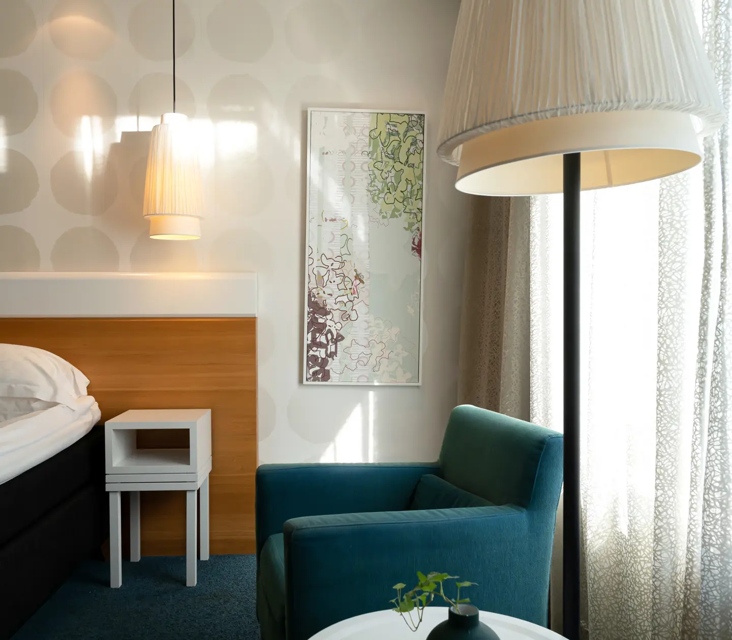 Mysigt hotellrum med säng, tavla och fåtölj