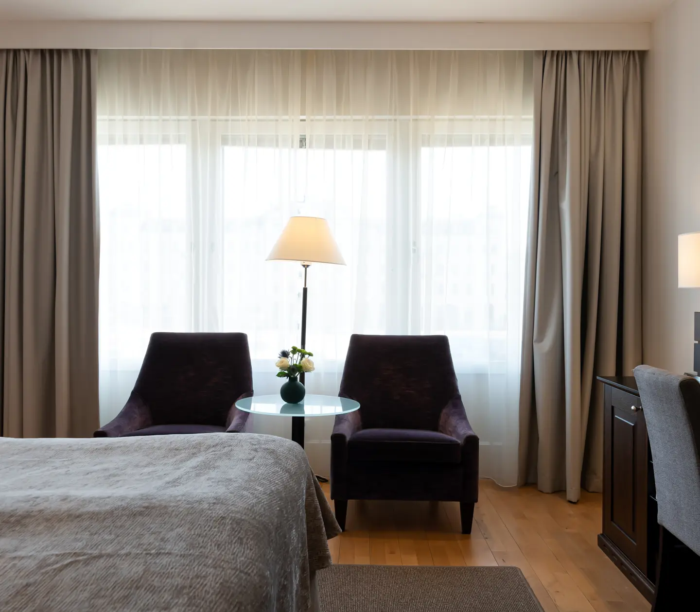 Ljust hotellrum med skrivbord, fåtöljer och fönster